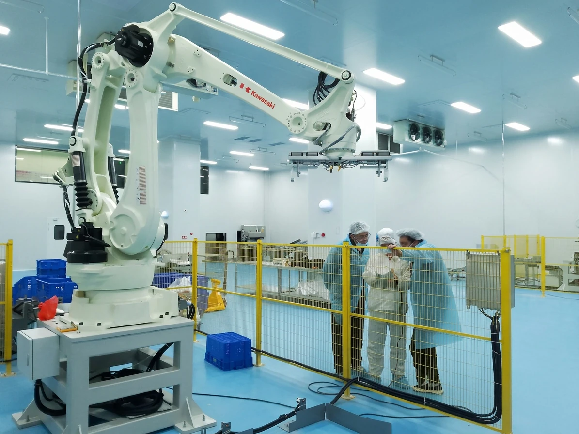 Food factory team evaluating an automated production system behind safety guarding