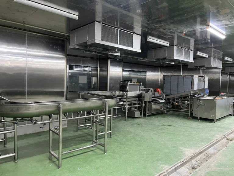 Connected stainless steel processing sections and conveyors inside a central food preparation facility