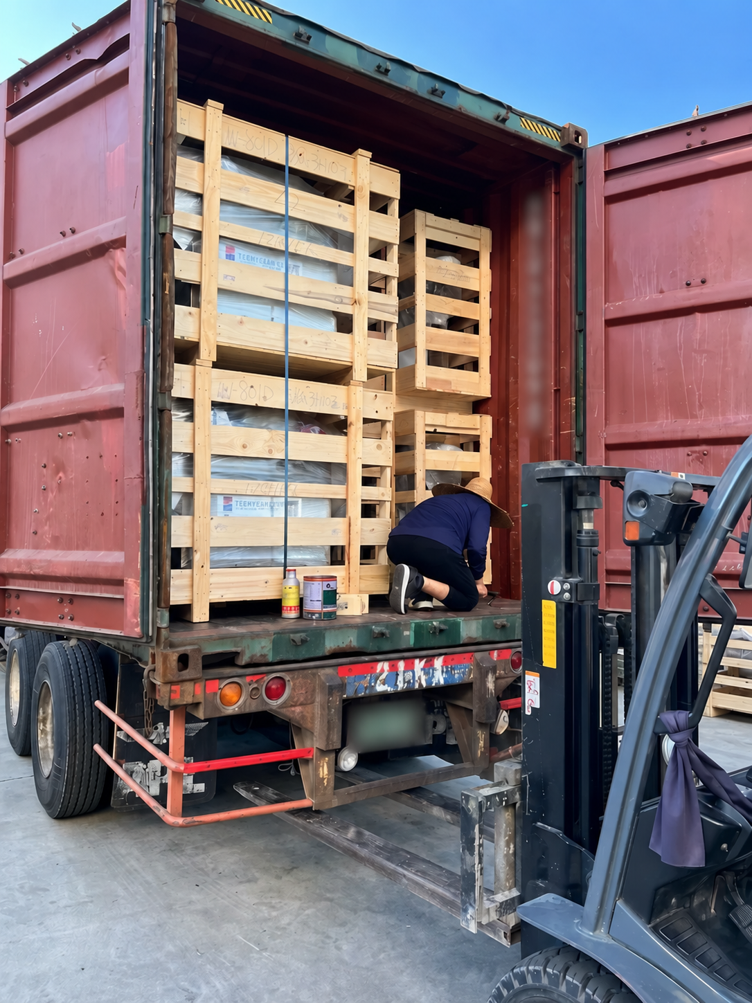 TEEMYEAH food processing equipment crates being loaded into a shipping container, with identifiers blurred