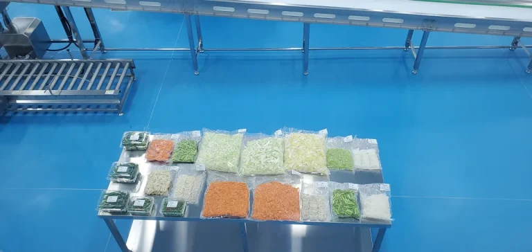 Packed prepared vegetables displayed beside processing and transfer equipment